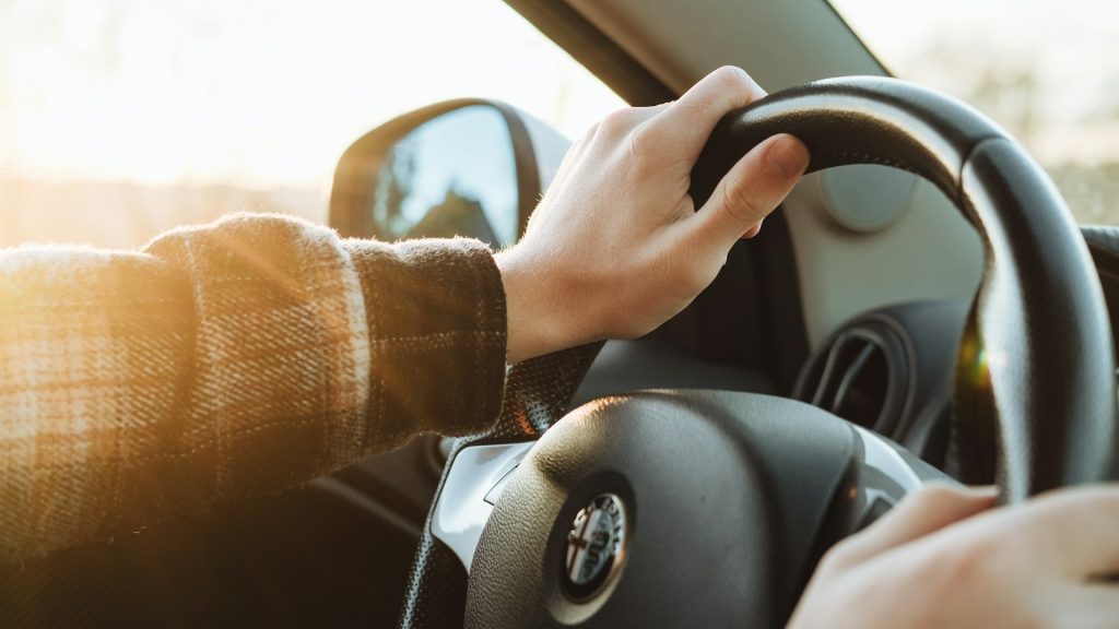 Handen aan het stuur tijdens zonnige omstandigheden, waarbij warmte en zonlicht het rijgedrag en reactievermogen beïnvloeden